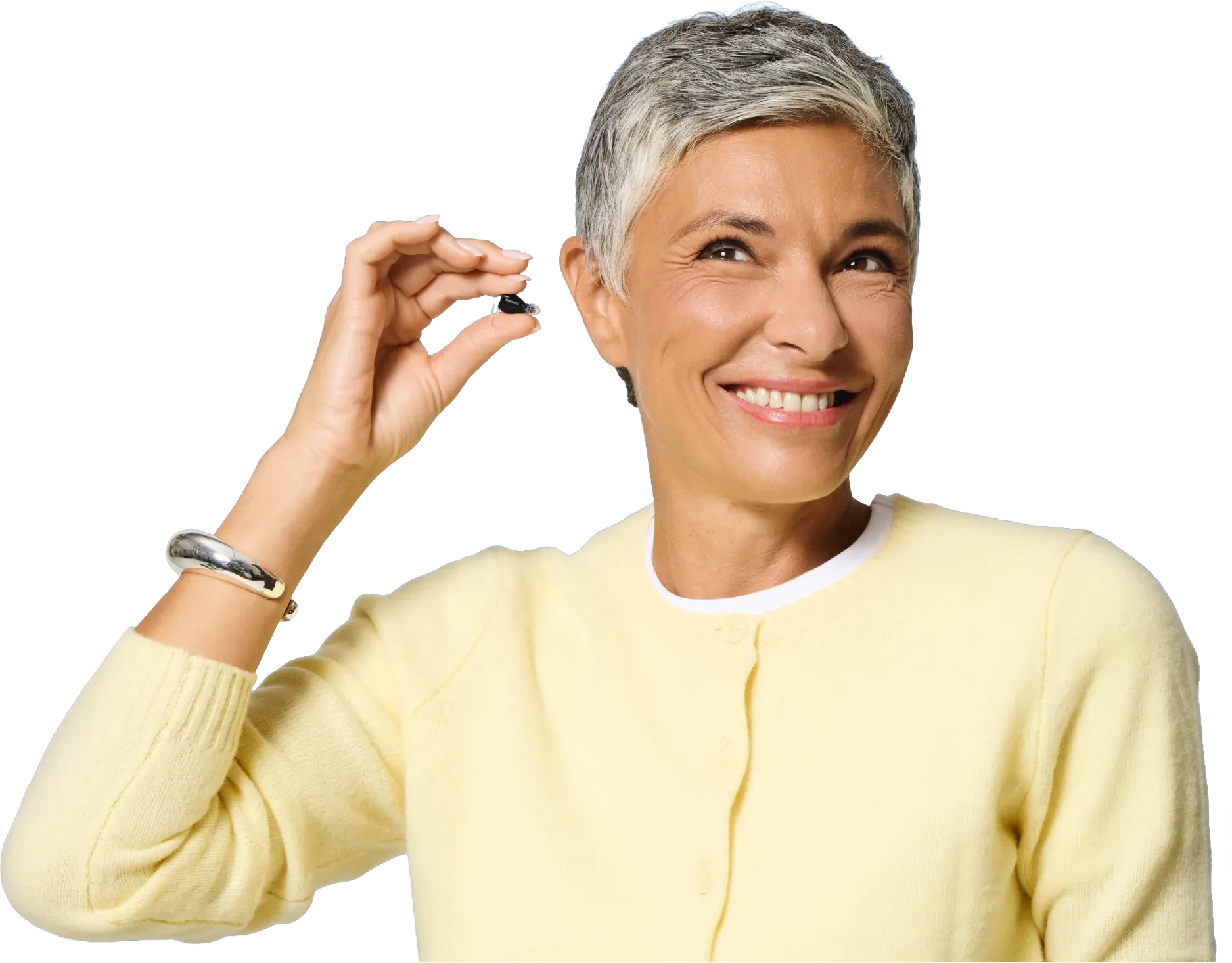 Mujer sonriendo mientras sostiene un audífono Philips HearLink NXT junto a su oído